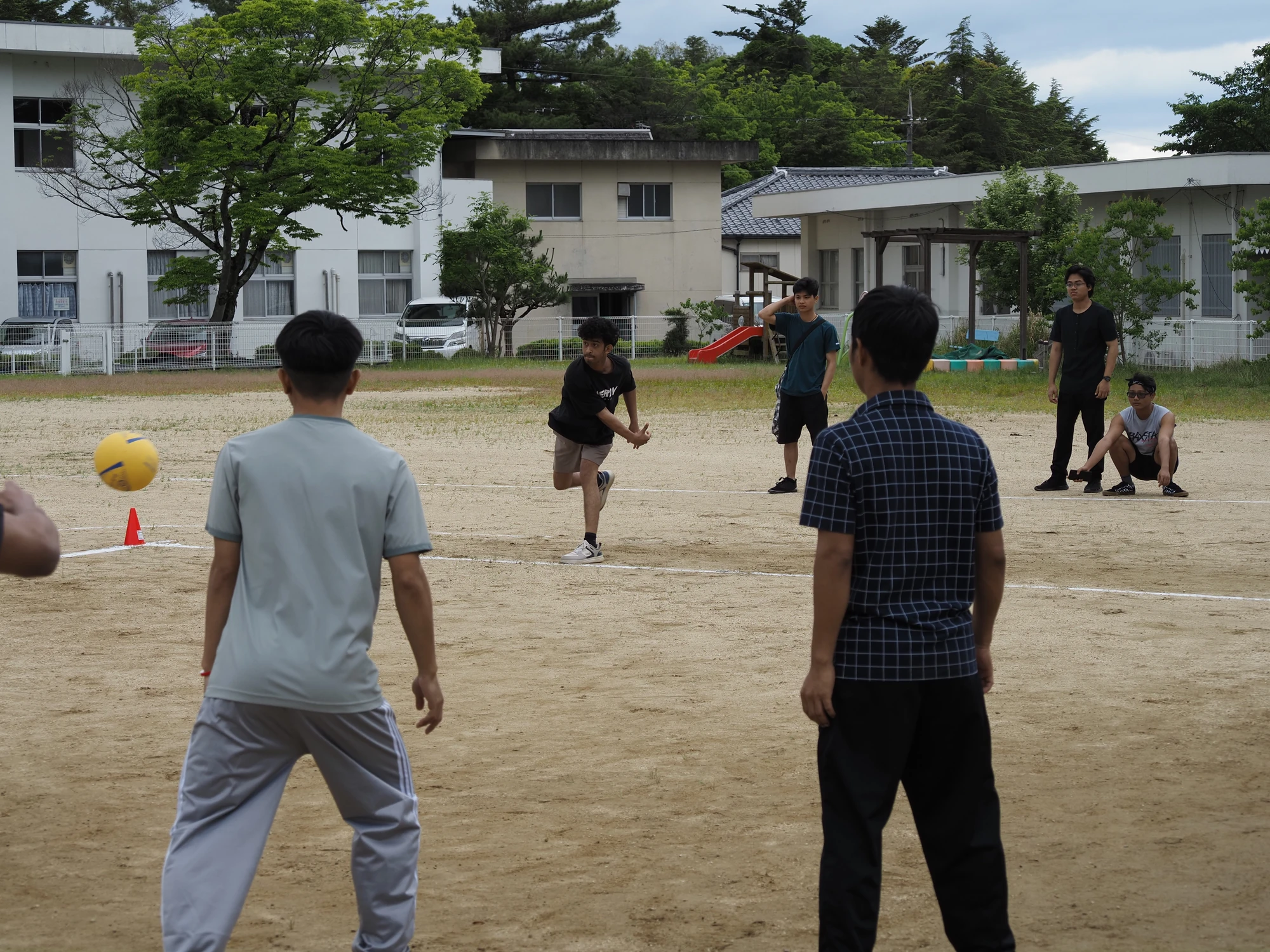 校舎を背景に校庭でスポーツを楽しむ学生たち